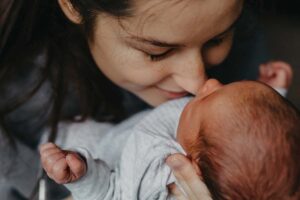 Young woman lovingly snuggling her newborn baby